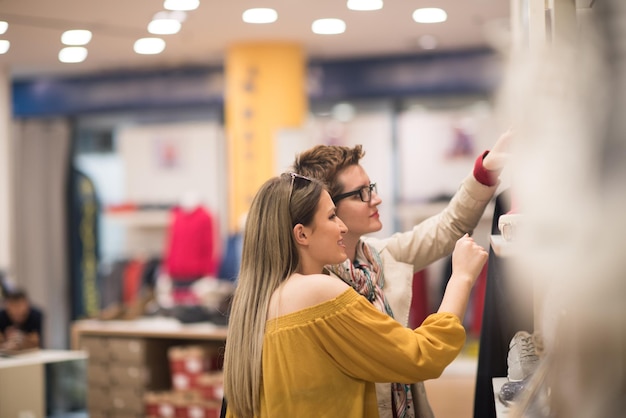 Deux Girl-Friends sur Shopping à pied sur le centre commercial avec des sacs et le choix