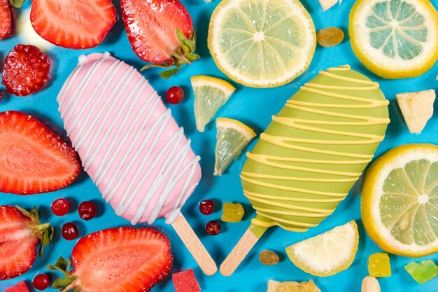 Deux glaces sur un bâtonnet fraise et citron sur fond bleu