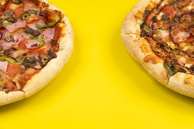 Deux grandes pizzas délicieuses différentes sur un fond jaune
