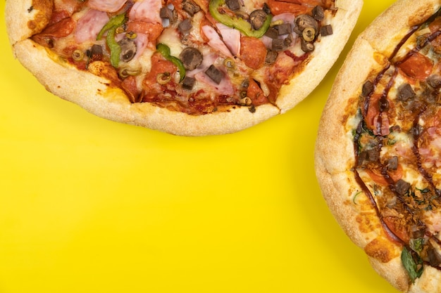 Deux grandes pizzas délicieuses différentes sur un fond jaune