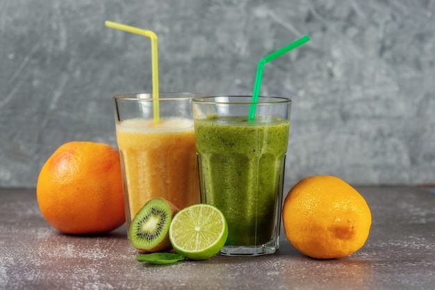 Deux grands verres de jus d'orange et un smoothie banane-orange kiwi et épinards