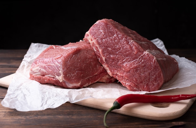 Deux gros morceaux de filet de veau, viande crue sur une planche à découper