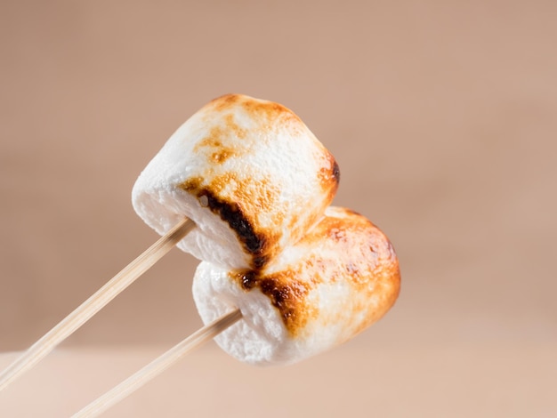 Photo deux guimauves sucrées avec croûte cuite sur fond marron.