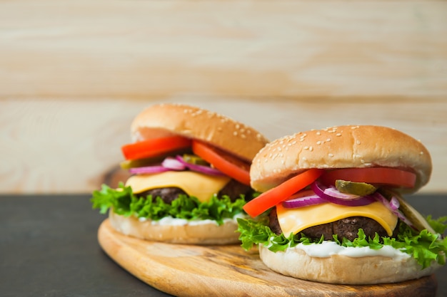 Deux hamburgers classiques sur planche de service en bois.