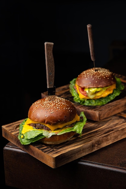 Deux hamburgers avec un couteau sur une planche de bois