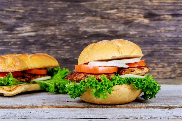 Deux hamburgers grillés faits maison avec du bœuf, de l&#39;oignon, des tomates, de la laitue et du fromage.