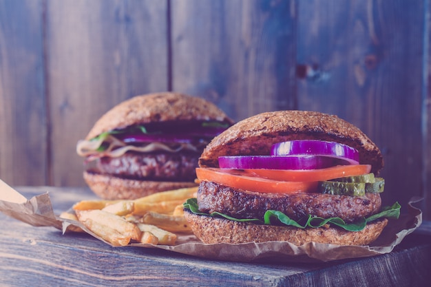 Deux hamburgers se bouchent sur une planche à découper. Style vintage.