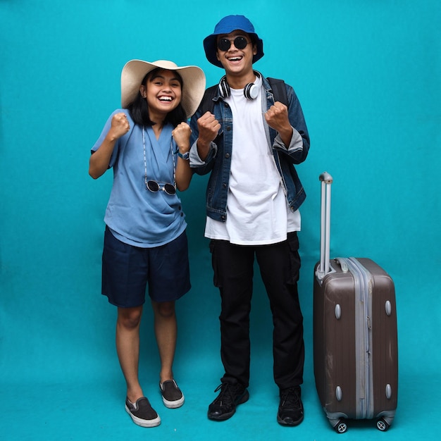 Deux heureux voyageur touriste femme et homme couple dans des vêtements décontractés font le geste du gagnant serrer le poing