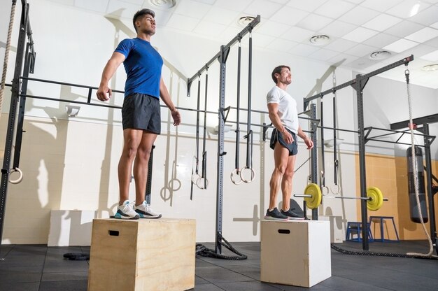 Deux homme sautant sur la boîte en forme au gymnase