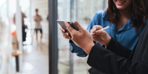 Deux hommes d'affaires asiatiques regardent une tablette et discutent de la stratégie d'entreprise en équipe.