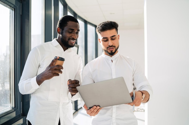 Deux hommes d'affaires interracial parlant avec un ordinateur portable