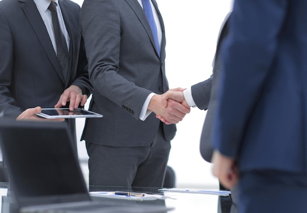 Deux hommes d'affaires joyeux se serrant la main avec le sourire au bureau avec leurs collègues
