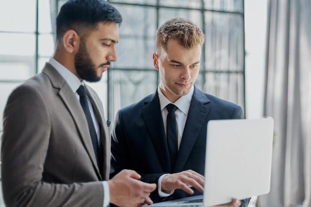 Deux hommes d'affaires professionnels discutant et utilisant un ordinateur de bureau au bureau