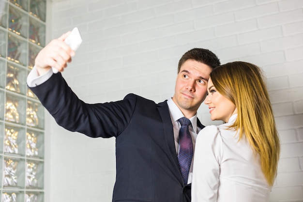 Deux hommes d'affaires prospères prenant un selfie heureux au bureau.