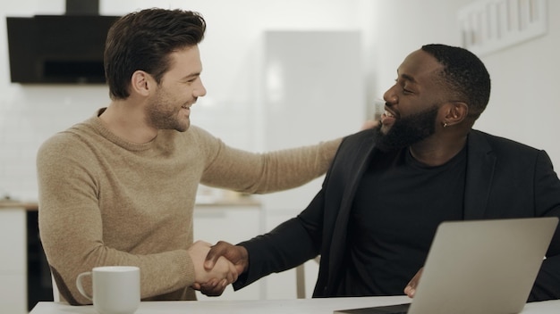 Photo deux hommes d'affaires se serrant la main dans une cuisine ouverte heureux partenaires discutant d'idées