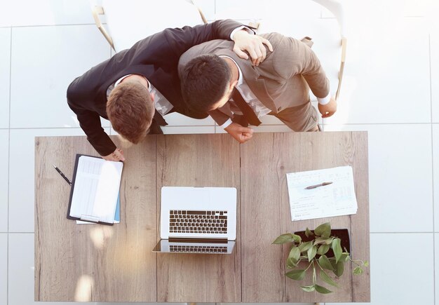 Deux hommes d'affaires souriants prospères travaillent sur une vue d'ordinateur portable d'en haut