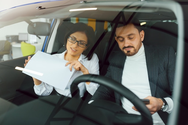 Deux hommes d'affaires en tenue classique analysent des documents assis dans la voiture.