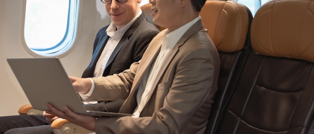 Deux hommes d'affaires travaillant ensemble sur un ordinateur portable pendant le vol