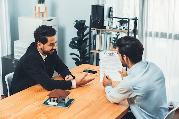 Deux hommes assis à un bureau, l'un d'eux signe un contrat.