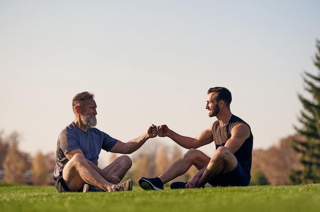 Les deux hommes assis sur l'herbe et saluant