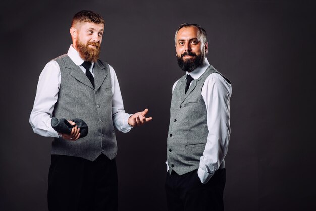 Deux hommes barbus en costumes parlant et gesticulant les uns aux autres sur le noir