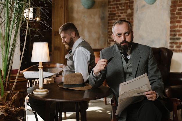 Deux hommes barbus vêtus de costumes à l'ancienne parlent ou discutent de quelque chose au restaurant