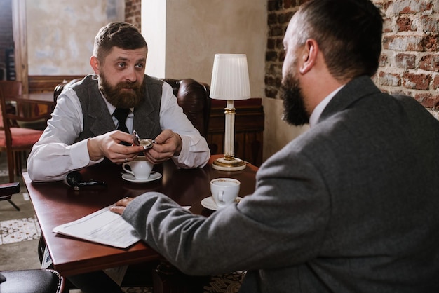 Deux hommes barbus vêtus de costumes à l'ancienne parlent ou discutent de quelque chose au restaurant