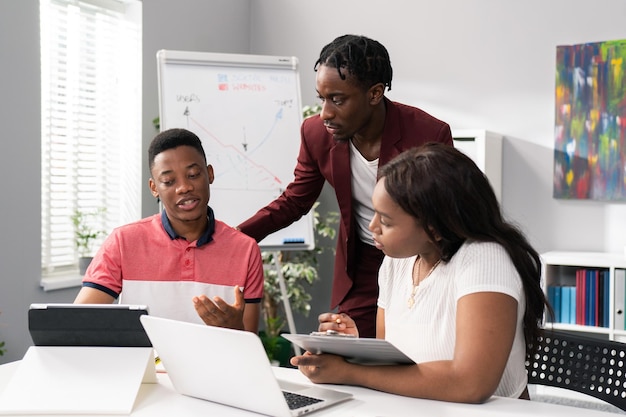 Deux hommes et une belle femme sont assis dans un bureau le matin pour préparer une conférence au travail