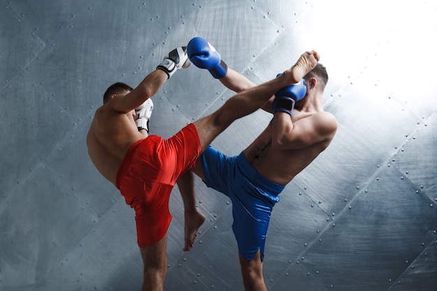 Deux hommes boxeurs combats muay thai kickboxing hgh kick steel background.