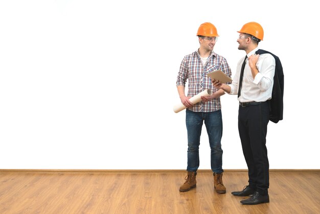 Les deux hommes en casques se tiennent avec une tablette sur le fond du mur blanc