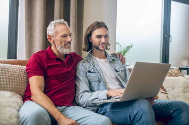 Deux hommes. Deux hommes assis l'un à côté de l'autre et regardant quelque chose sur un ordinateur portable