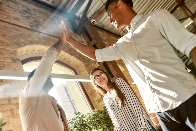 deux hommes donnant highfive tout en se tenant avec des collègues dans le travail d'équipe de bureau moderne