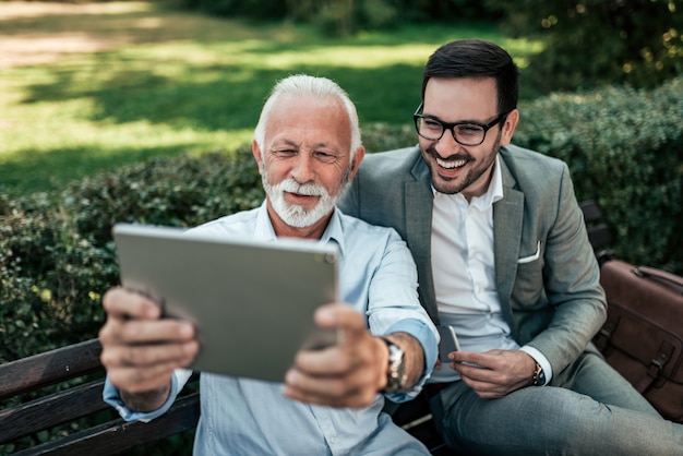 Deux hommes élégants prenant selfie sur une tablette à l&#39;extérieur.