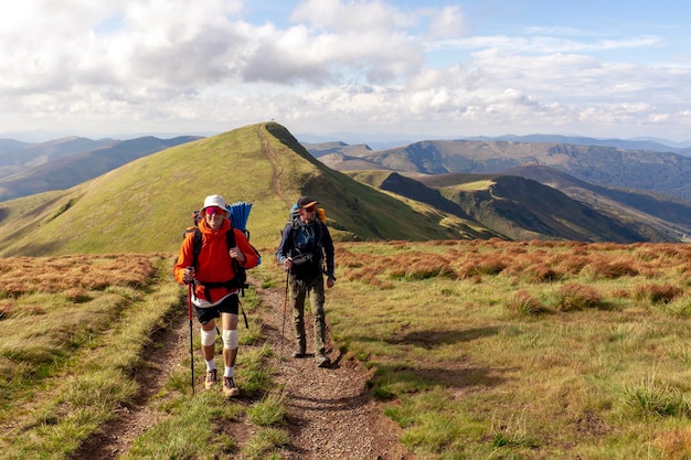deux hommes avec équipement de randonnée et sacs à dos vont à la montagne avec des bâtons de randonnée