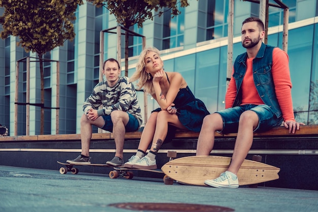 Deux hommes et une femme avec des longboards posant dans la rue dans un style urbain.