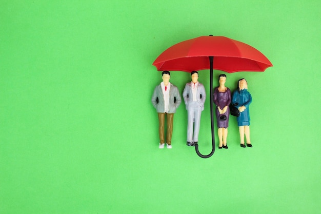 deux hommes et femmes miniatures sous un concept de couverture d'assurance parapluie