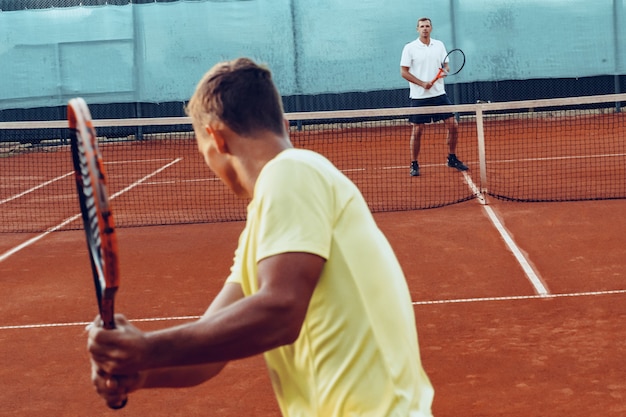 Deux hommes jouant au tennis sur terrain de tennis en terre battue