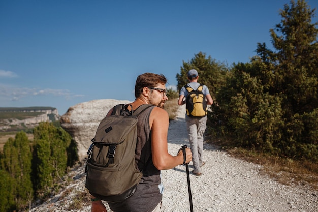 Deux hommes marchant sur une pente rocheuse portant des sacs à dos à l'aide de bâtons de trekking