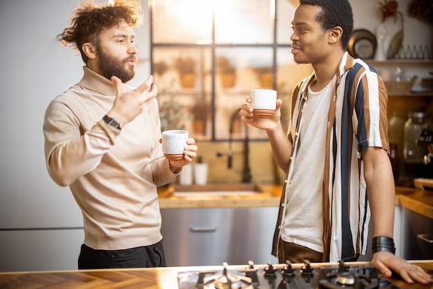 Deux hommes parlant et buvant du café dans la cuisine à la maison