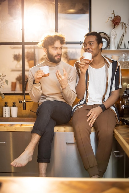 Deux hommes parlant et buvant du café dans la cuisine à la maison