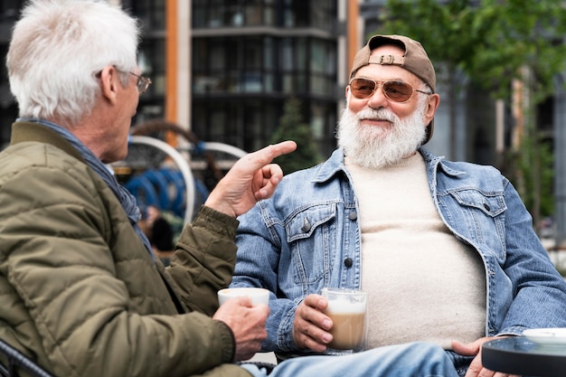 Deux hommes plus âgés de la ville prenant un café ensemble et discutant