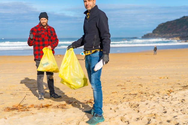 Deux hommes ramassant du plastique sur la plage Concept d'écologie pollution de la mer