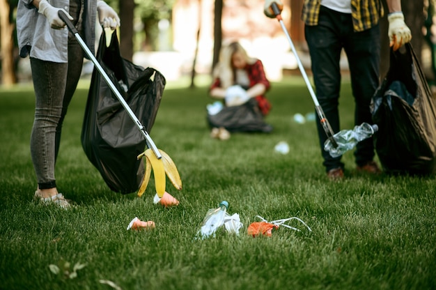 Deux hommes ramassent des déchets plastiques dans des sacs dans un parc, faisant du bénévolat. Personne de sexe masculin nettoie la forêt, la restauration écologique, le mode de vie écologique, la collecte et le recyclage des déchets, les soins écologiques, le nettoyage