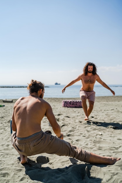 Deux hommes s'échauffant avant l'entraînement sur une plage de sable