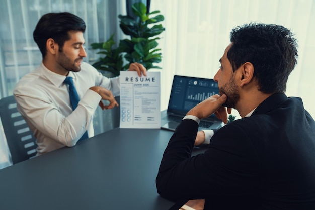 Deux hommes sont assis à une table avec un CV devant eux.