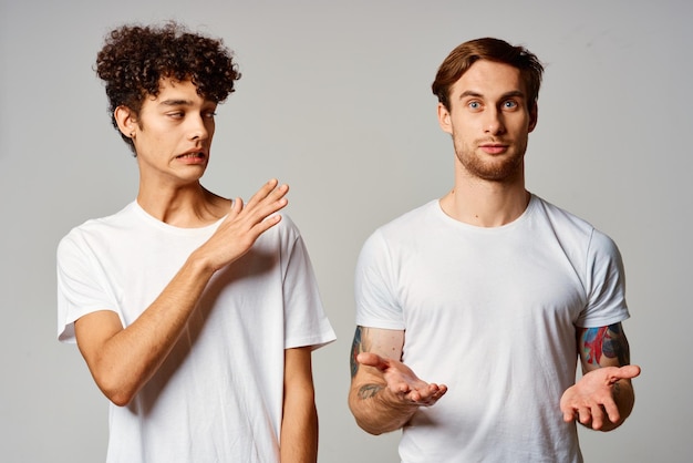 Photo deux hommes en t-shirts blancs se tiennent à côté des émotions d'amitié photo de haute qualité