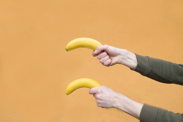 Deux Hommes Tiennent Deux Bananes Contre Sur Un Mur Orange