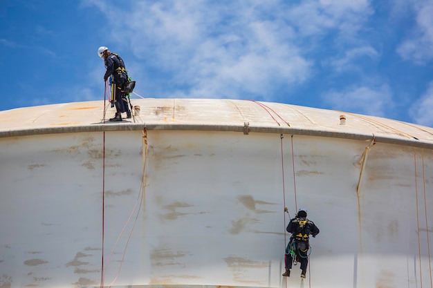 Deux hommes vers le bas de la hauteur du toit du réservoir du travailleur de l'accès à la corde d'inspection de sécurité de l'épaisseur de la soudure du réservoir de stockage de gaz