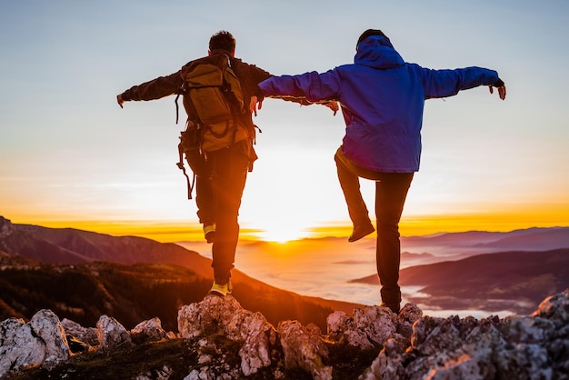 Photo deux hommes voyageurs debout sur une jambe sur le sommet de la montagne concept de pic d'un mode de vie actif et sain