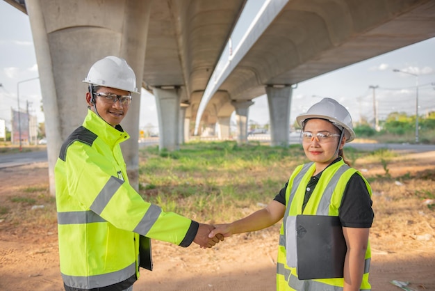 Deux ingénieurs discutent des travaux sur le site d'un grand pont en constructionDes consultants en gestion discutent avec des ingénieurs de l'avancement et de la planification de la construction de l'autoroute